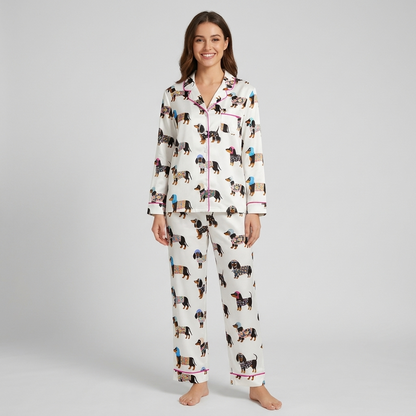 Women's satin pajama set with black-and-tan dachshunds in floral coats and knit hats on white - long sleeve and pants