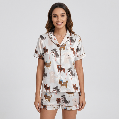 Women's satin pajama set with small dogs in knit caps and sweaters trailing red leashes on white - short sleeve and shorts