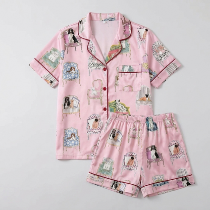 Women's long-sleeve satin pajama set with spaniels lounging on tufted armchairs on pink - flat lay