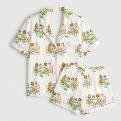 Women's satin pajama set with fluffy dogs in pearls and crowns at green mahjong tables on white with pink piping - flat lay