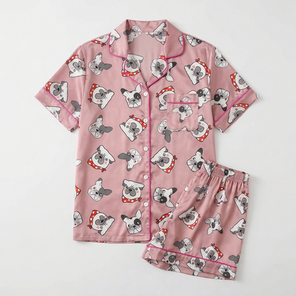 Women's satin pajama set with squishy French bulldog faces in red heart bows on soft pink - flat lay