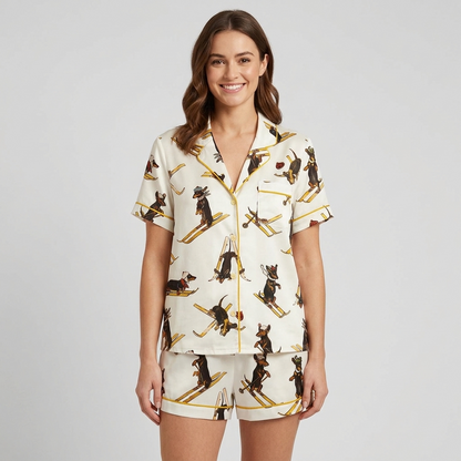 Women's satin pajama set with vintage dachshunds in knit caps skiing on golden skis on white - short sleeve and shorts