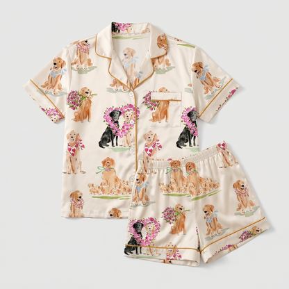 Women's satin pajama set with golden retrievers and a black Lab holding pink roses in flower hearts on cream - flat lay