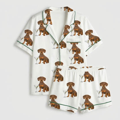 Women's satin pajama set with dachshunds beside martini glasses with olives on white with green piping - flat lay
