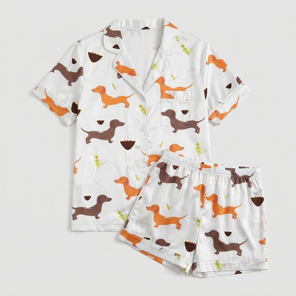 Women's satin pajama set with orange and brown dachshunds with wine glasses and martinis on white - flat lay