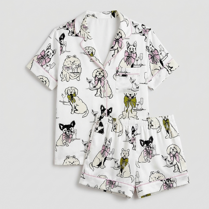Women's satin pajama set with sketchy black-and-white dogs wearing pink and olive bows on white - flat lay
