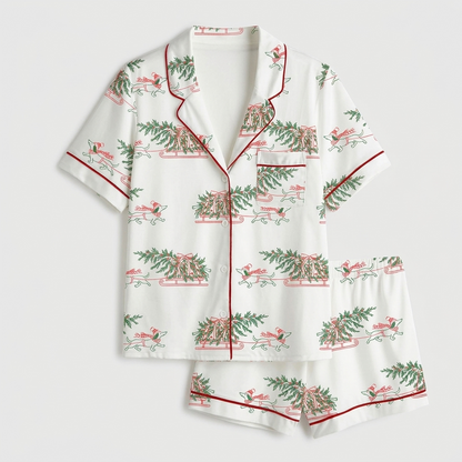Women's satin pajama set with sketched dachshunds pulling sleighs under pine garlands on white - flat lay