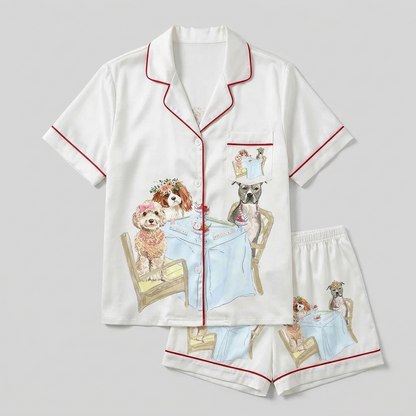 Women's satin pajama set with two dogs in flower crowns and tiaras at a mahjong table on white with red piping - flat lay