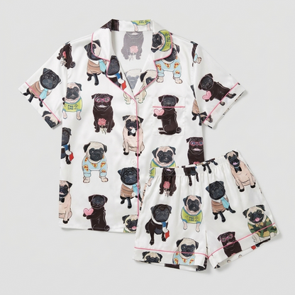 Women's satin pajama set with fawn and black pugs in sweaters, sunglasses and ties on white with pink piping - flat lay