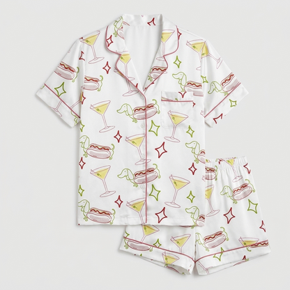 Women's satin pajama set with martinis, hot dogs and dachshund outlines on white with sparkly stars - flat lay
