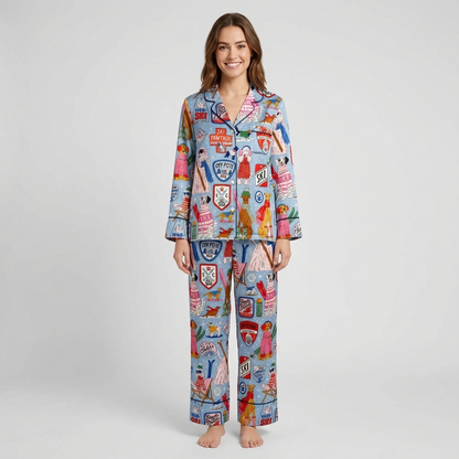 Women's satin pajama set in light blue with dogs in knit sweaters and shades among ski badges and gear - long sleeve and pants