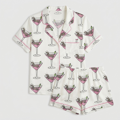 Women's satin pajama set with tiny dachshunds in pink martini glasses with olives on white - flat lay