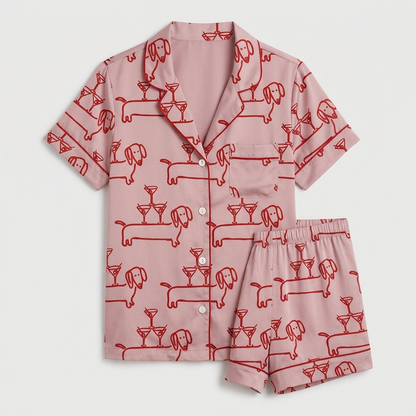 Women's long-sleeve satin pajama set with dachshunds and cocktail glasses in red line art on blush pink - flat lay