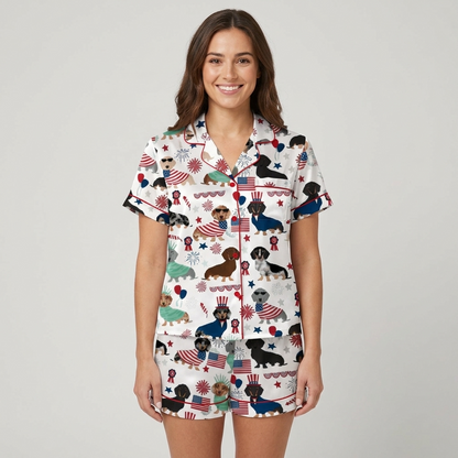 Women's satin pajama set with dachshunds in flag capes and Liberty crowns beside fireworks and stars on white - short sleeve and shorts