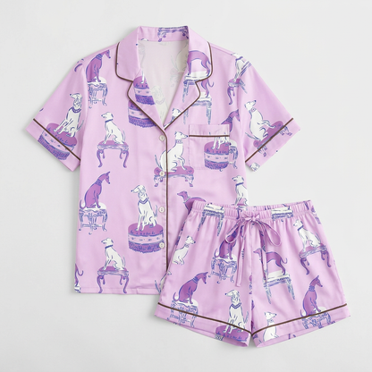 Women's satin pajama set with lilac and white greyhounds on antique stools on soft lavender with brown piping - flat lay