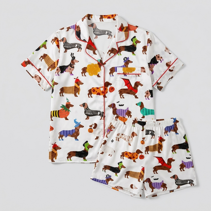 Women's satin pajama set with dachshunds in pumpkin suits and witch hats with candy and bats on white - flat lay
