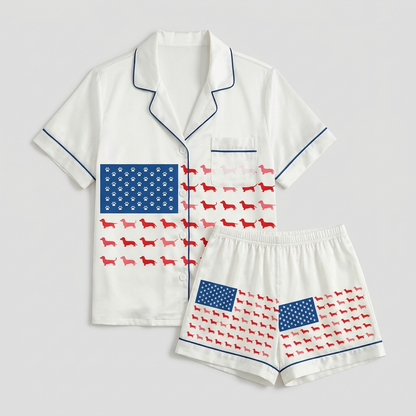 Women's satin pajama set with a flag of paw prints and red dachshunds across the chest on white - flat lay