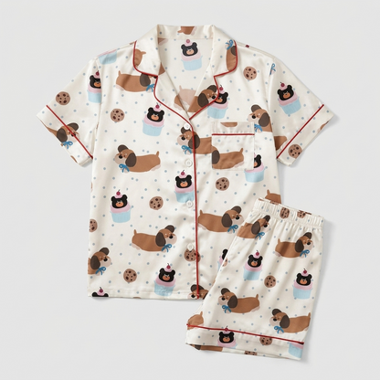 Women's satin pajama set with dachshunds in bow ties with cookies and cupcakes on white - flat lay
