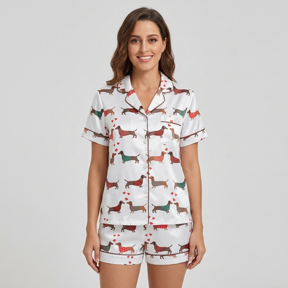 Women's satin pajama set with dachshunds in red, green and teal sweaters among tiny hearts on white - short sleeve and shorts