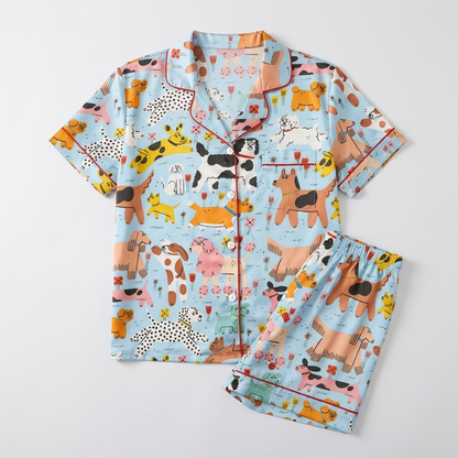 Women's satin pajama set with wobbly colorful dogs among flowers and bones on sky blue - flat lay