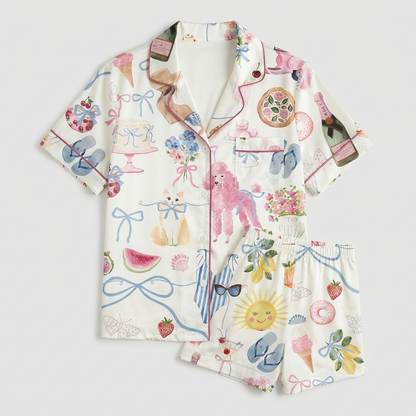 Women's satin pajama set with a pink poodle among spritz glasses, lemons and a smiling sun on white - flat lay