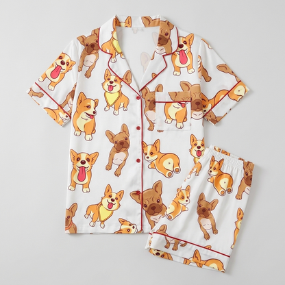 Women's satin pajama set with smiling corgis and fawn French bulldogs with tongues out on white - flat lay