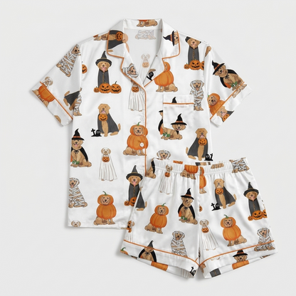 Women's satin pajama set with golden retrievers in witch hats, mummy wraps and ghost sheets on white - flat lay