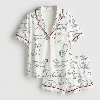 Women's satin pajama set with navy line-drawn dachshunds with red script on white - flat lay