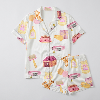 Women's satin pajama set printed DOG MOM with bones, treats, bowls and a pink doghouse on white - flat lay