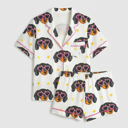 Women's satin pajama set with dachshund faces in pink heart sunglasses and tiny gold stars on white - flat lay