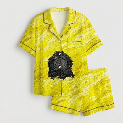 Women's satin pajama set with one shaggy black dog on a yellow painted field - flat lay