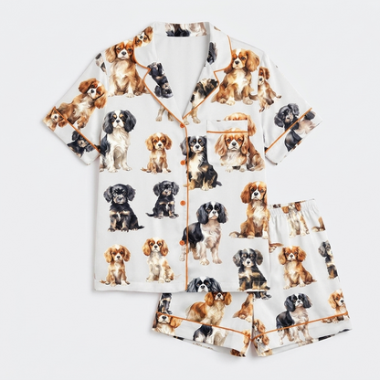 Women's long-sleeve satin pajama set with Cavalier King Charles spaniels in ruby, tricolor and black-and-tan on white - flat lay