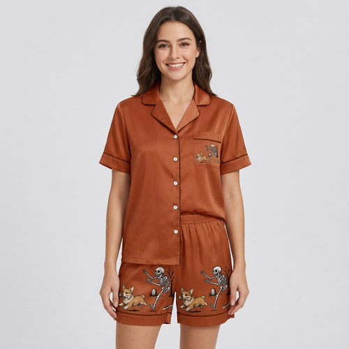 Women's satin pajama set with a skeleton chasing a corgi past a graveyard tree on rust brown - short sleeve and shorts