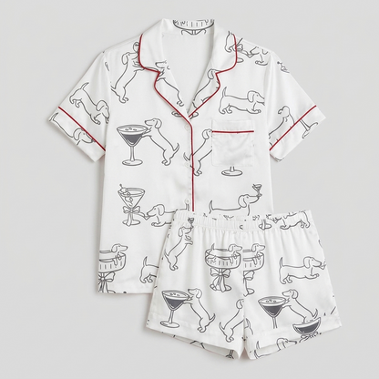 Women's satin pajama set with black outline dachshunds and martini glasses on white with red piping - flat lay