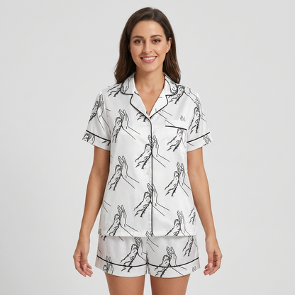 Women's satin pajama set with a black line drawing of a hand high-fiving a dog paw on white - short sleeve and shorts