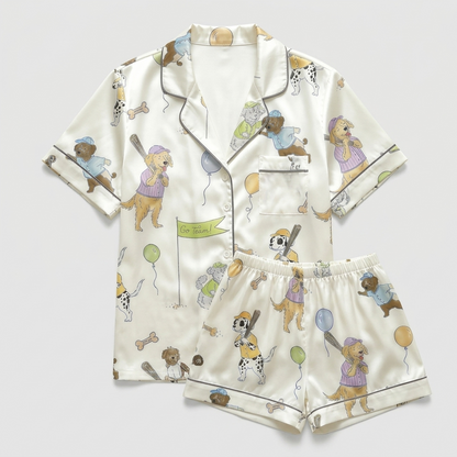 Women's satin pajama set with dogs in caps and jerseys swinging bats on cream - flat lay