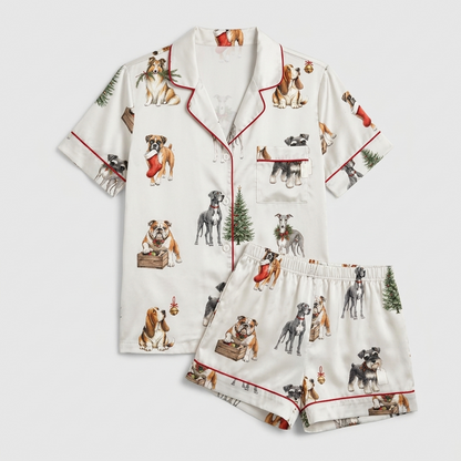 Women's satin pajama set with schnauzers, bulldogs and spaniels by evergreen trees, stockings and gift crates - flat lay