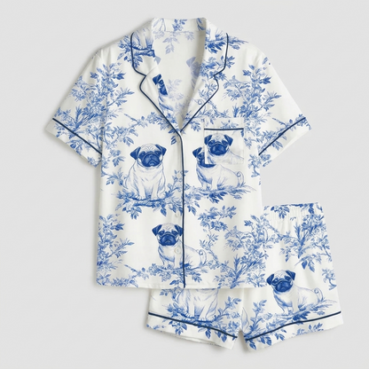Women's satin pajama set with pug faces in blue and white garden leaves - flat lay