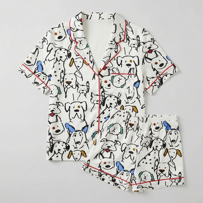Women's satin pajama set with black line-drawn dogs and dalmatians with blue and mustard ears on white - flat lay