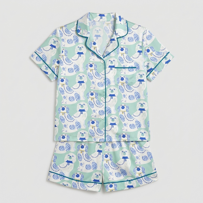 Women's satin pajama set with blue and white porcelain spaniel figurines in lattice frames on mint green - flat lay