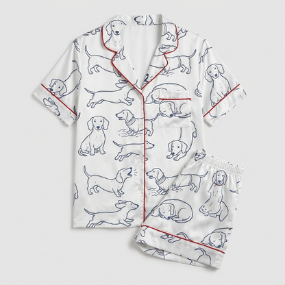 Women's satin pajama set with navy line-drawn dachshunds with red script on white - flat lay
