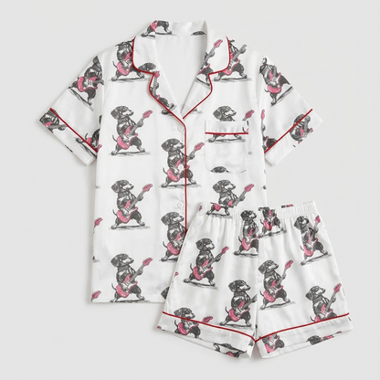 Women's satin pajama set with a black dachshund playing electric guitar on white with red piping - flat lay