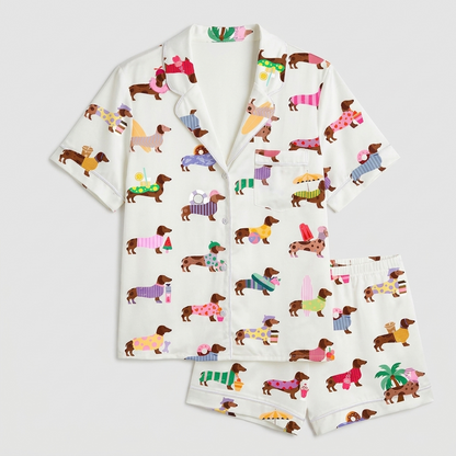 Women's satin pajama set with dachshunds in sweaters, palm trees and ice cream cones on white - flat lay