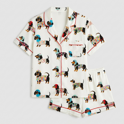 Women's satin pajama set with dachshunds in flowery sweaters and knit hats on white with red piping - flat lay