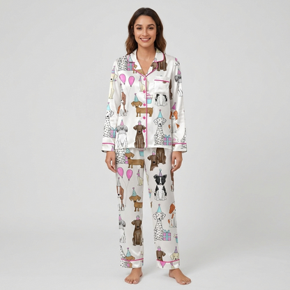 Women's satin pajama set with dogs in party hats beside pink balloons, cupcakes and wrapped gifts on white - long sleeve and pants