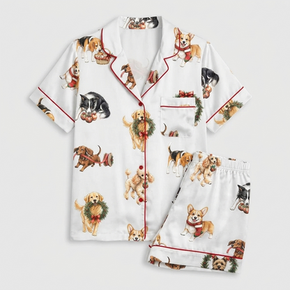 Women's satin pajama set with retrievers, beagles and terriers popping through holly wreaths on white - flat lay