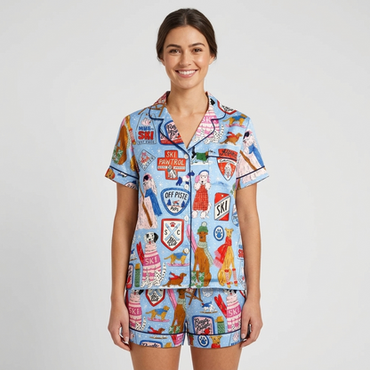 Women's satin pajama set in light blue with dogs in knit sweaters and shades among ski badges and gear - short sleeve and shorts