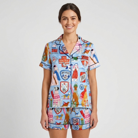 Women's satin pajama set in light blue with dogs in knit sweaters and shades among ski badges and gear - short sleeve and shorts