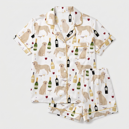 Women's satin pajama set with cream golden retrievers, wine bottles and goblets on white with gold piping - flat lay